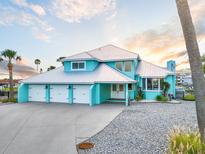 Stunning waterfront home featuring a metal roof, turquoise paint, and a three-car garage at 744 Spanish Main Dr, Apollo Beach, FL 33572