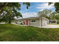 Charming single-story home featuring a red front door and picturesque landscaping at 10517 Blossom Lake Dr, Seminole, FL 33772