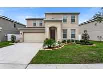 Two-story home featuring neutral color scheme, attached garage, and well-maintained landscaping at 12017 Grand Kempston Dr, Gibsonton, FL 33534