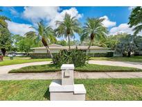 Landscaped front yard with tropical plants, palm trees, circular driveway, and charming mailbox at 2216 El De Oro Dr, Clearwater, FL 33764