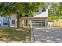 Contemporary two-story home with a modern glass garage door and stone facade at 3411 W El Prado Blvd, Tampa, FL 33629