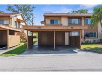 Cozy townhouse with covered parking, showing unit numbers 4424 and 4420 under a bright blue sky at 4424 Pelorus Dr, New Port Richey, FL 34652