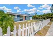 Charming blue home featuring a well-manicured lawn and classic white picket fence at 5367 5Th N Ave, St Petersburg, FL 33710