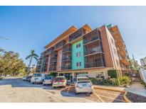 Condominium building with a colorful exterior and screened-in balconies above a parking area on a sunny day at 750 Burlington N Ave # 4L, St Petersburg, FL 33701