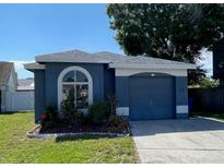 Charming single-story home with a well-manicured lawn, arched window, and attached one-car garage at 8608 Twin Farms Pl, Tampa, FL 33635