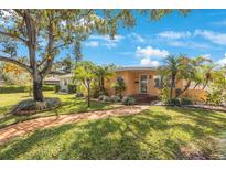 Charming home featuring mature trees, lush landscaping, and a welcoming brick pathway at 110 27Th Ne Ave, St Petersburg, FL 33704