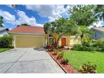 Inviting single-story home showcasing well-maintained landscaping, a driveway, and a cheerful yellow exterior at 14119 Stonegate Dr, Tampa, FL 33624