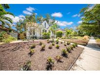 Charming home with landscaped yard featuring mature trees and beautiful plantings under a sunny blue sky at 150 23Rd N Ave, St Petersburg, FL 33704