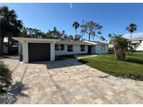 Charming single-story home with a beautifully paved driveway and lush tropical landscaping under a clear, sunny sky at 204 162Nd Ave, Redington Beach, FL 33708
