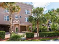 Multi-story home exterior with palm trees, manicured landscaping, and covered parking at 600 Reserve Ln, Dunedin, FL 34698