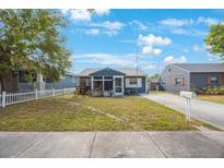 Charming single-story blue home featuring a screened-in porch and a well-maintained front yard at 940 57Th N Ave, St Petersburg, FL 33703