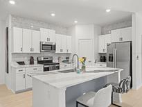 Modern kitchen features white cabinets, stainless appliances, and a large center island with stone countertops at 9617 Branching Ship Trce, Wesley Chapel, FL 33545