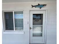 A white front door with a screen and address number, located next to a window and a shark decoration at 2077 Canal Dr # L35, Bradenton, FL 34207