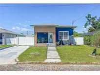Charming blue home featuring a modern wood accent, well-manicured lawn, and inviting walkway at 2711 W Cordelia St, Tampa, FL 33607