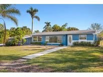 Charming blue single-story home featuring a well-manicured front yard, sidewalk and lush landscaping at 3500 Gussie St, Punta Gorda, FL 33950