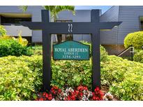 Community sign for Royal Aberdeen Lodge 22 surrounded by lush green landscaping and colorful flowers at 36750 Us 19 N # 22212, Palm Harbor, FL 34684