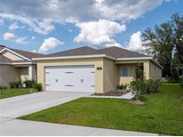 Charming single-story home with a two-car garage, manicured lawn, and inviting curb appeal under a blue sky at 3686 Zephyr Preserve Pl, Zephyrhills, FL 33541