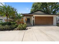 Charming home featuring a well-manicured lawn, beautiful landscaping, and a spacious two-car garage at 1509 Coachlight Way, Dunedin, FL 34698