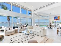 Bright, open living room with floor-to-ceiling windows offering panoramic waterfront views at 16496 Redington Dr, Redington Beach, FL 33708