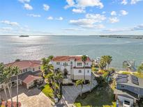 Expansive waterfront estate with a red tile roof and lush tropical landscaping offering panoramic ocean views at 2402 Baywood W Dr, Dunedin, FL 34698