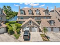 A charming townhouse showcasing an exterior elevation, featuring a two-car garage, balcony and picturesque lake views at 2782 Countryside Blvd # 2, Clearwater, FL 33761