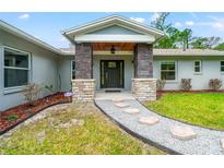 Charming front entrance featuring stone accents, gray siding, and a decorative stone walkway at 28628 Bennington Dr, Wesley Chapel, FL 33544