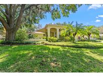 Well-maintained front yard with lush green lawn, mature trees, and manicured landscaping accentuating this yellow home's facade at 3022 Forest Club Dr, Plant City, FL 33566