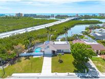 Beautiful single-story home featuring a private pool, lush landscaping, and solar panels on a sunny day with a water view at 7906 Bayshore Dr, Seminole, FL 33776