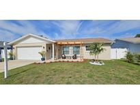 Inviting home exterior with a well-manicured lawn, patio seating, and charming pergola at 10884 118Th St, Seminole, FL 33778