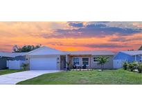 Charming single-Gathering home with a well-manicured lawn and cozy front porch seating area under a beautiful sunset sky at 10884 118Th St, Seminole, FL 33778