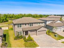 An appealing exterior view of this two-story home featuring a three-car garage and well-maintained landscaping at 12107 Nouveau Ave, Spring Hill, FL 34610