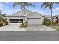 Charming single-story home with attached two-car garage, lush landscaping, and well-manicured lawn at 2419 Richmond Greens Ct, Sun City Center, FL 33573