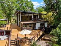 Modern two-story home with a spacious deck, floor-to-ceiling windows, and outdoor seating at 4701 Rambling River Rd, Brandon, FL 33511