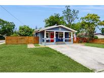 Charming single-story home featuring a cozy front porch, well-maintained lawn, and a vibrant red front door at 1202 E Caracas St, Tampa, FL 33603
