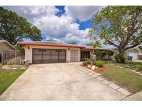Charming single-story home featuring a well-kept lawn, mature trees and a two-car garage at 1874 Cameo Way, Clearwater, FL 33756