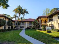 Beautiful condo building with tropical landscaping, sidewalk, and building sign at 2306 Hammock Pine Blvd # 2306, Clearwater, FL 33761