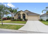 Charming single-story home with a manicured front yard, lush landscaping, and a two-car garage at 2404 Dovesong Trace Dr, Ruskin, FL 33570