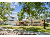 Charming single-story home with a well-maintained lawn and mature trees, set against a blue sky at 2607 S Bryant Cir, Tampa, FL 33629