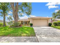 Charming single-story home featuring a well-manicured lawn, mature tree, and two-car garage at 3360 Masters Dr, Clearwater, FL 33761