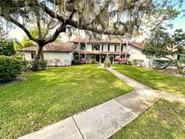 Inviting two-story home with a lush green lawn and mature trees draped with Spanish moss at 5454 Saddlebrook Way # 2, Wesley Chapel, FL 33543