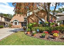 Charming single-Gathering home with brick facade, mature trees, and colorful landscaping in the front yard at 7591 Harbor View Way, Seminole, FL 33776