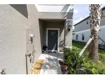Inviting front door with gray stucco facade and stone landscaping detail and a pleasant, covered entryway at 8299 Crescent Oaks Dr, New Port Richey, FL 34655