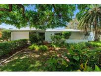 Charming single-story home with lush landscaping and mature trees offering shade and curb appeal at 838 Park Ct, Palm Harbor, FL 34683