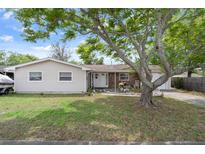 Inviting single-Gathering home with a well-manicured front lawn, mature shade trees, and a cozy, welcoming entrance at 9414 Northcliffe Blvd, Spring Hill, FL 34606