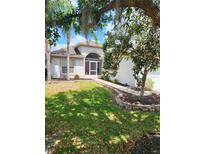 Charming single-story home with a screened front porch, lush lawn, and mature trees enhancing its curb appeal at 9608 Rolling Cir, San Antonio, FL 33576