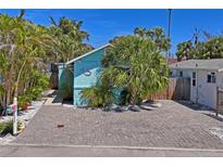 Charming blue home with lush tropical landscaping and a brick paver driveway at 13123 4Th E St, Madeira Beach, FL 33708