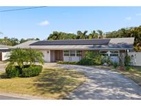 Charming ranch-style home with a brick facade, mature landscaping, and solar panels on the roof at 1720 Emerald Dr, Clearwater, FL 33756