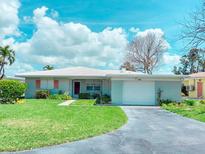 Charming single-story home with a well-manicured lawn and a paved driveway leading to an attached garage at 179 Bath Club N Blvd, North Redington Beach, FL 33708