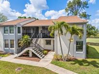 Exterior of condo featuring stairs, two palm trees, green grass, and blue skies with white clouds at 2017 Skimmer W Ct # 416, Clearwater, FL 33762