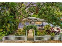 Charming purple home features a lush front yard and a welcoming white picket fence at 522 James St, Dunedin, FL 34698